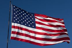 American Flag Waving In Wind Against a Deep Blue Sky.