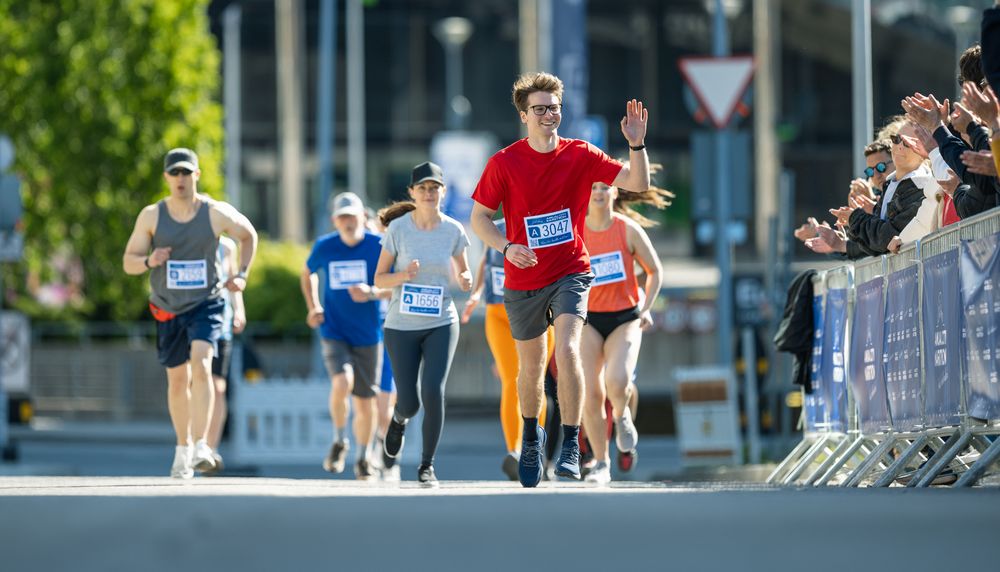 Shot of a Group of Diverse People Running in a Marathon and Waving to their Loved Ones and Supporters in the Audience.