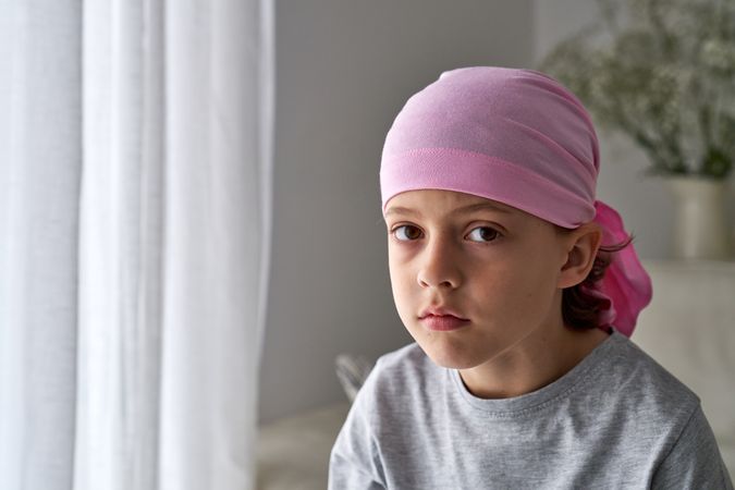 Serious boy in pink bandana symbol of breast cancer