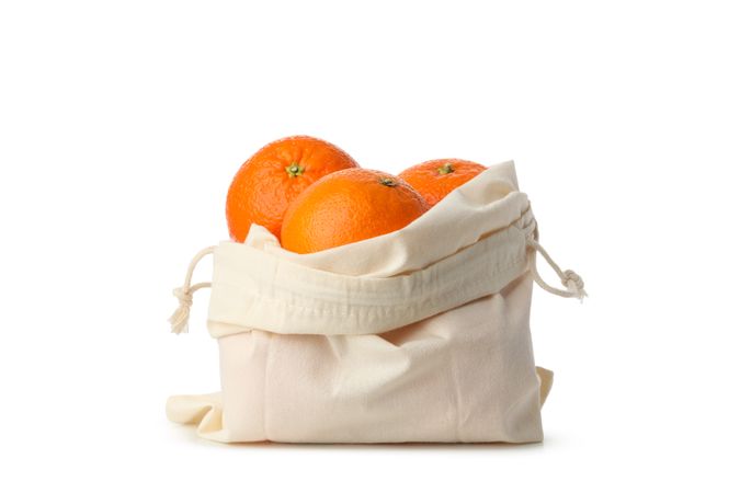 Cotton bag with ripe mandarins isolated on light background