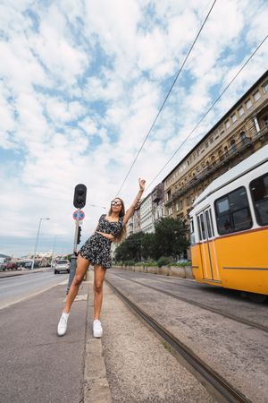 Stylish woman stopping tram with raised hand