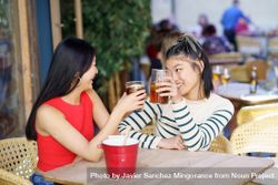 Two women sitting in restaurant patio enjoying their drinks 5XkLr0