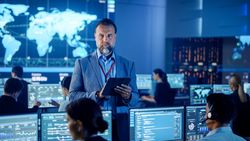 Diverse Team in a Modern Control Center Analyzes Global Data on Multiple Screens