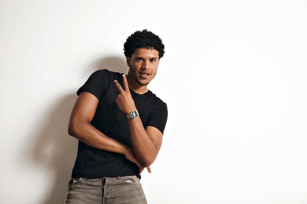 Male model in dark clothes giving peace sign in bright room