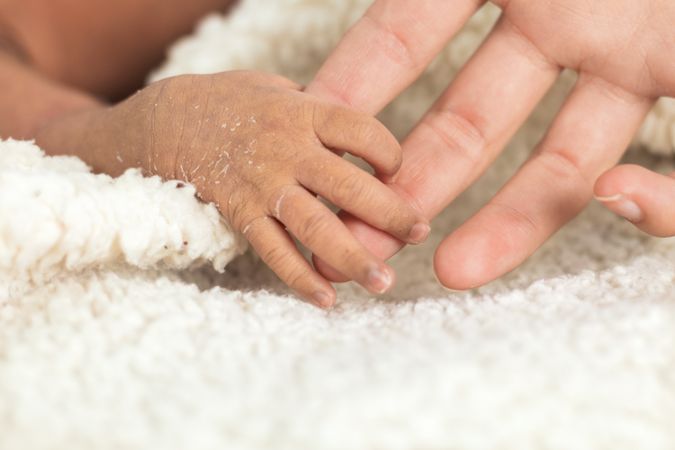 Anonymous mother holding newborn baby tiny hand