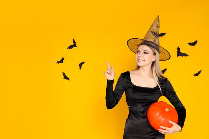 Concept of Halloween, young woman on yellow background