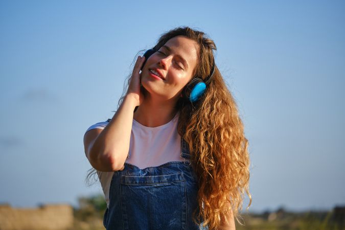 Carefree woman listening to music in headphones in nature