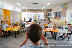 Parrot standing on a boy's head looking at his classmate in classroom 4mG1W0
