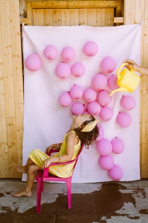 Kids having fun with watering can against wall with balloons