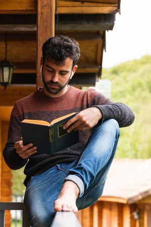 Pensive man chilling on terrace with book