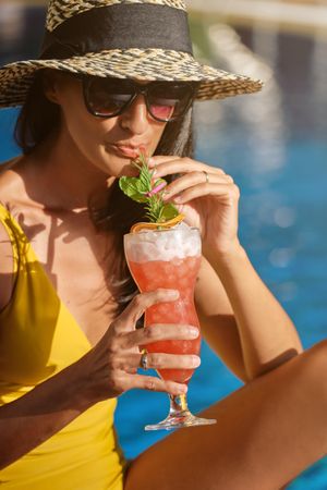 Stylish woman enjoying cocktail on poolside