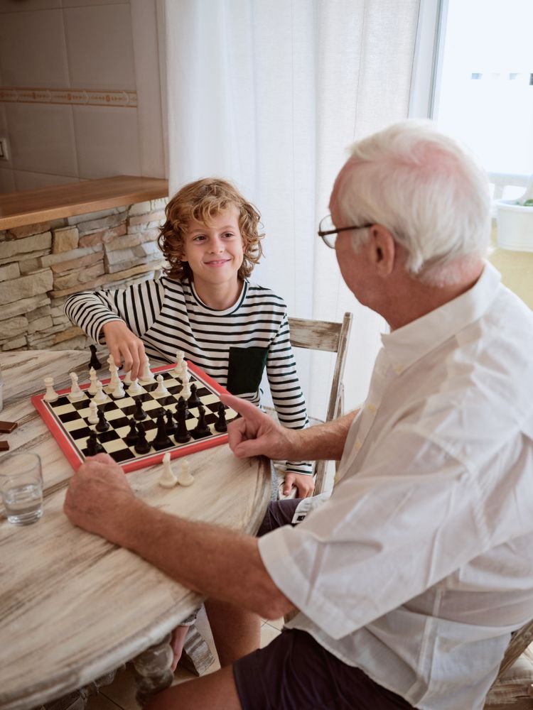 Grandfather and grandson playing board game in cozy kitchen