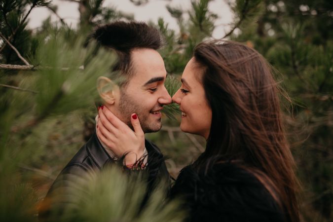 Happy couple hugging among pine forest