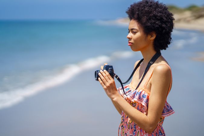 Woman with camera at the coast of beautiful beach
