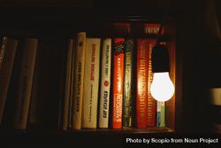Light bulb beside bookshelf inside dark room 4ZrZ34