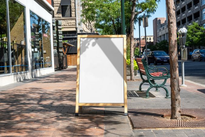 A-frame mockup on street on shops with tree shadow