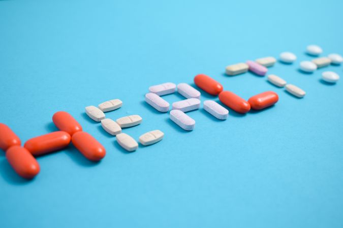 Multiple pills spelling the word "HEALTH" on blue table