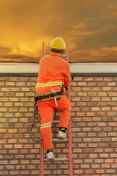 Man with yellow bump cap climbing a ladder