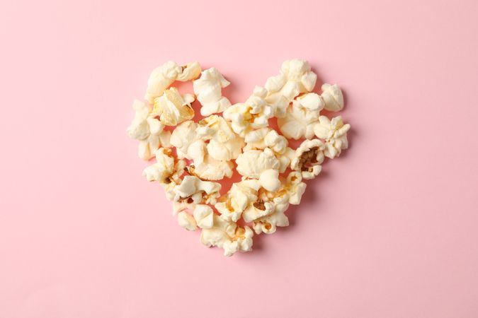 Flat lay composition with popcorn heart on pink background, space for text