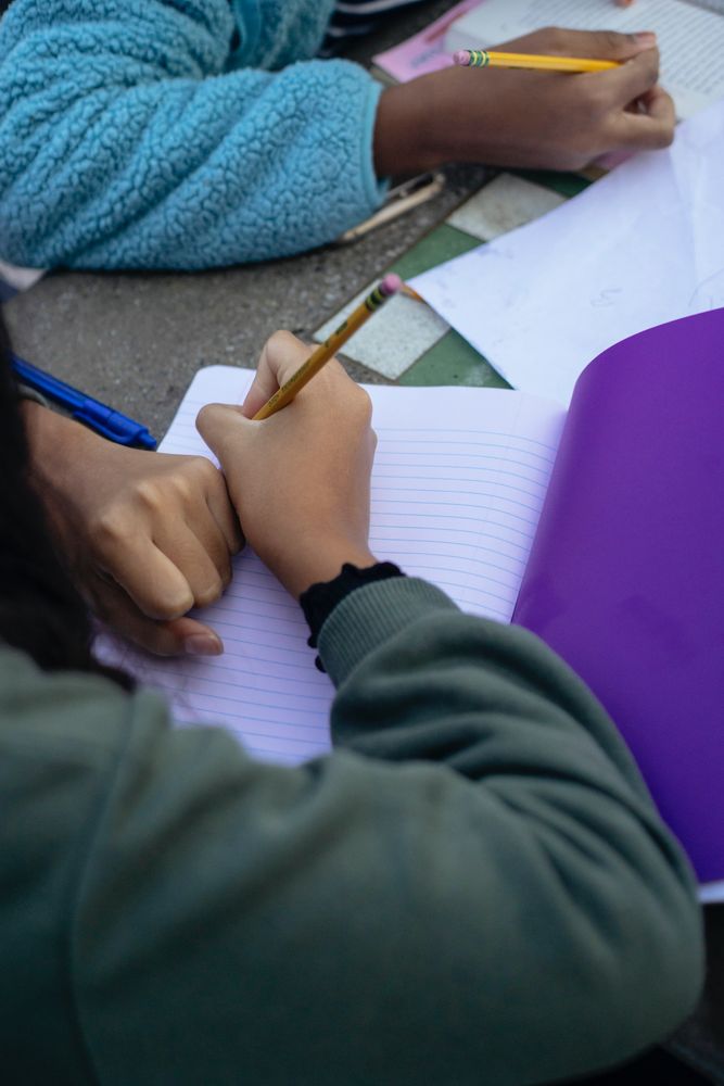 Close-up shot of two children writing in a notebook