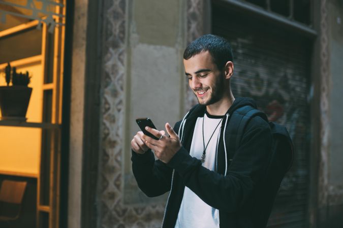 Man smiling while looking down at cell phone