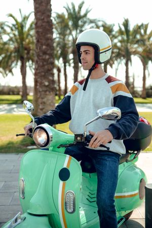 Man in motorcycle helmet sitting on bike and smiling