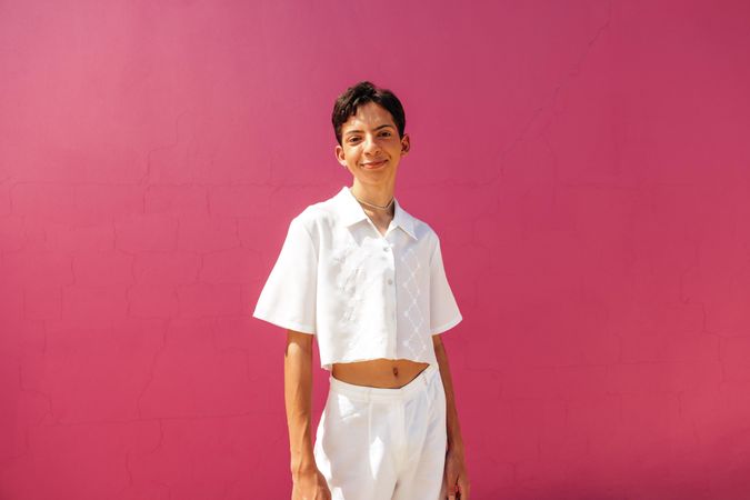 Carefree young gay man standing against a pink background with copy space