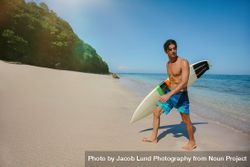 Male surfer holding surf board walking out of the sea 5oDVrQ