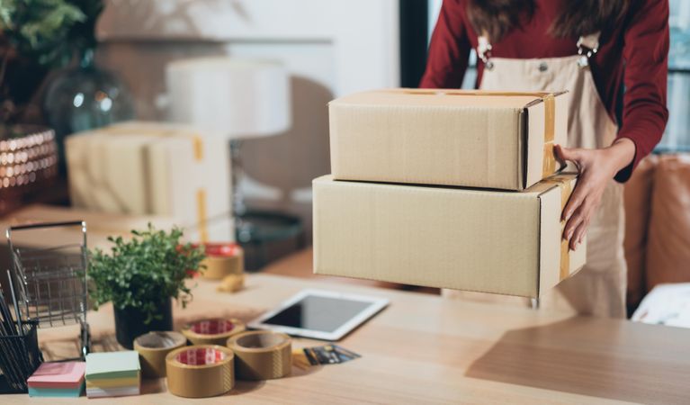Woman working from home with boxes for shipment
