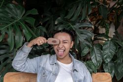 A young Hispanic woman is posing and smiling with an ice cream