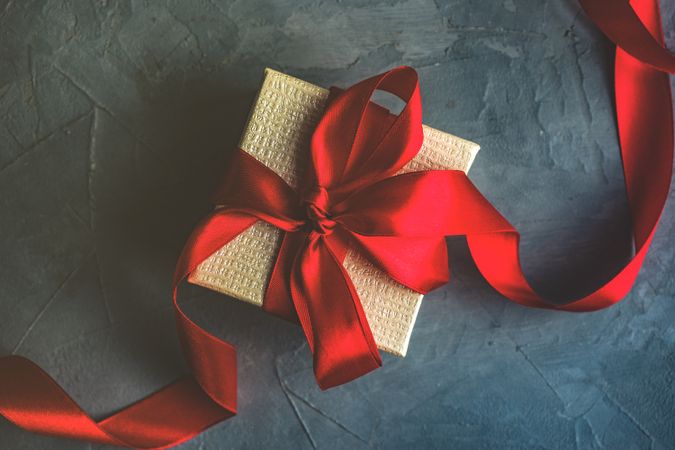 Single gift box with red ribbon on concrete