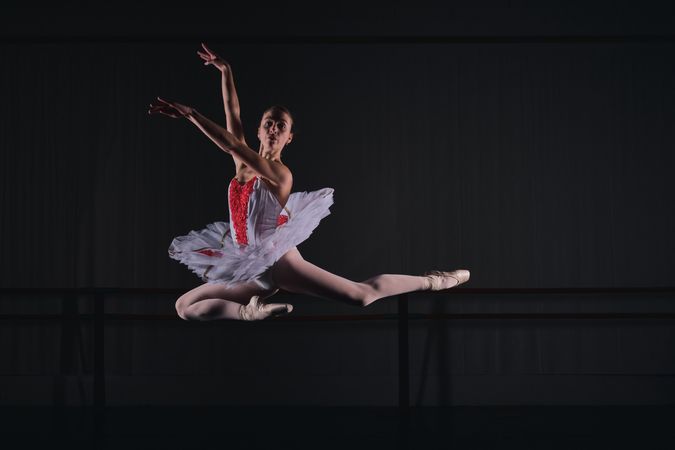 Flexible woman ballerina jumping while dancing ballet role