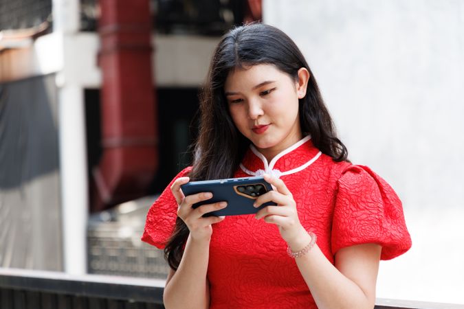 Asian woman in Chinese New Year costume texting on mobile phone