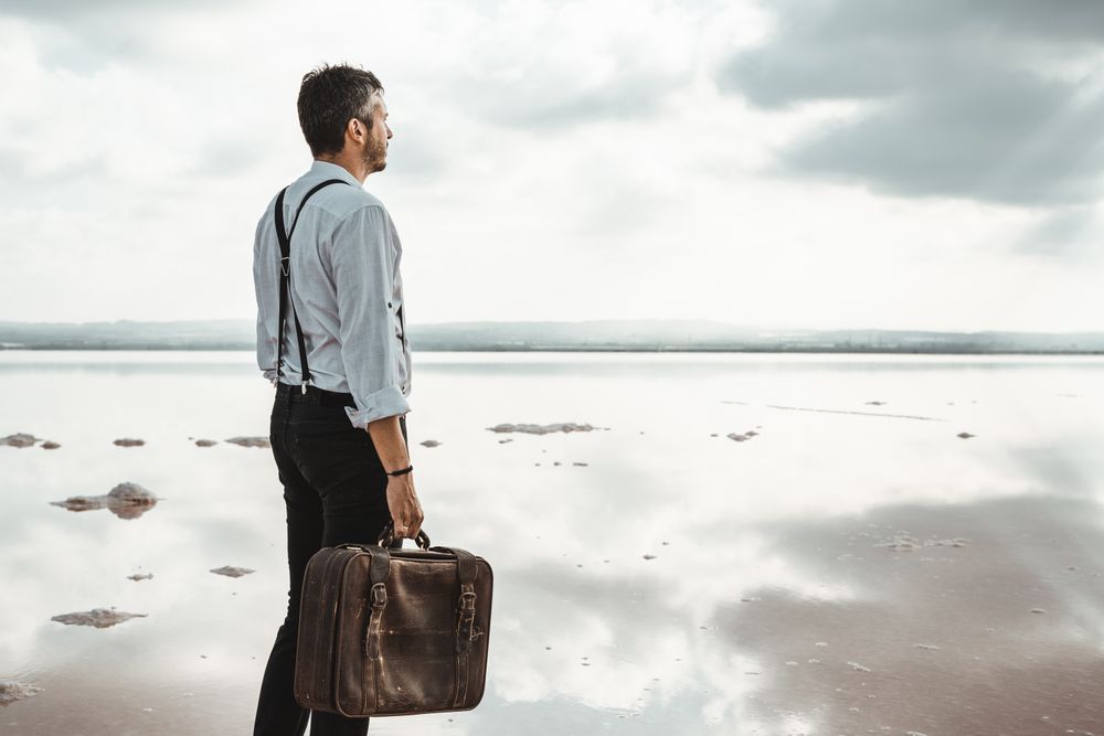 Fancy man with suitcase gazing at seaside