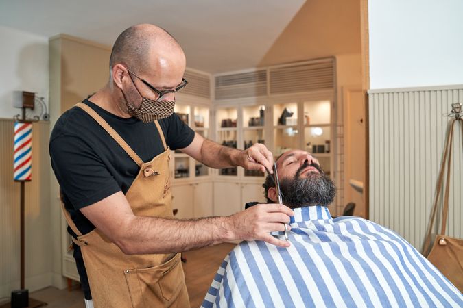 Barber cutting hair of client in barbershop