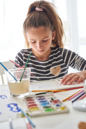 Focused girl painting on paper