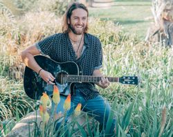 Hipster man in meadow with guitar