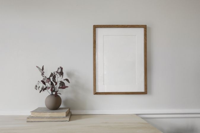 Blank vertical wooden picture frame mock up on wooden table.