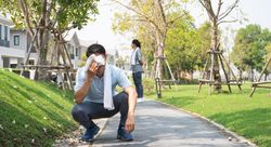 Male crouched on walkway taking a break during workout