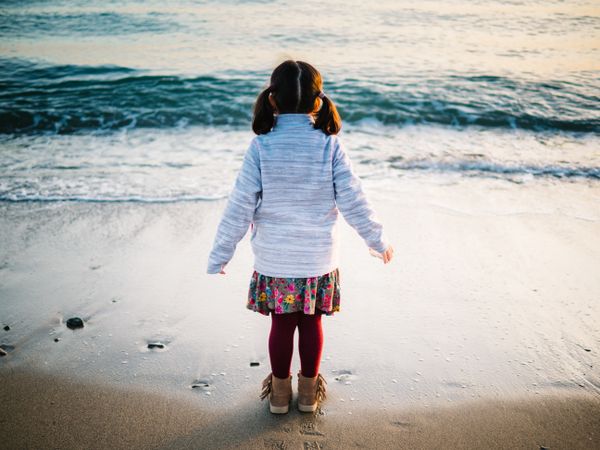 back view of little girl looking at sea