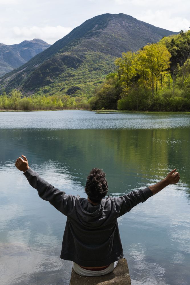 Carefree traveling man enjoying freedom near lake in mountains