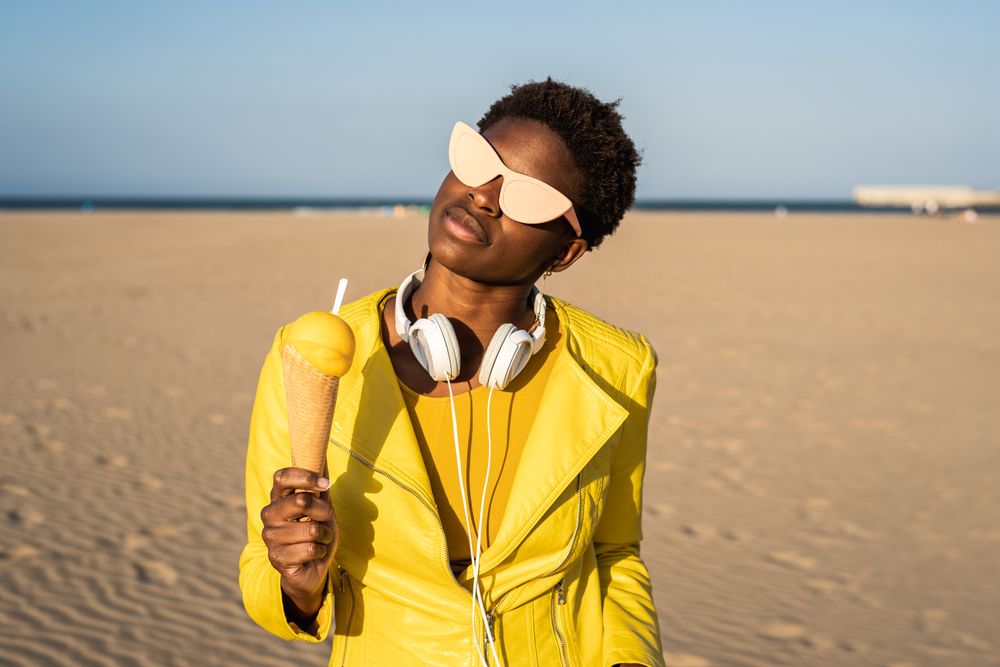 Cool female eating ice cream on beach