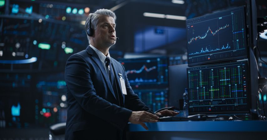 Portrait of a Stock Exchange Broker Working on Computer with Multi-Screen Workstation with Real-Time Stocks, Commodities and Exchange Market Charts.