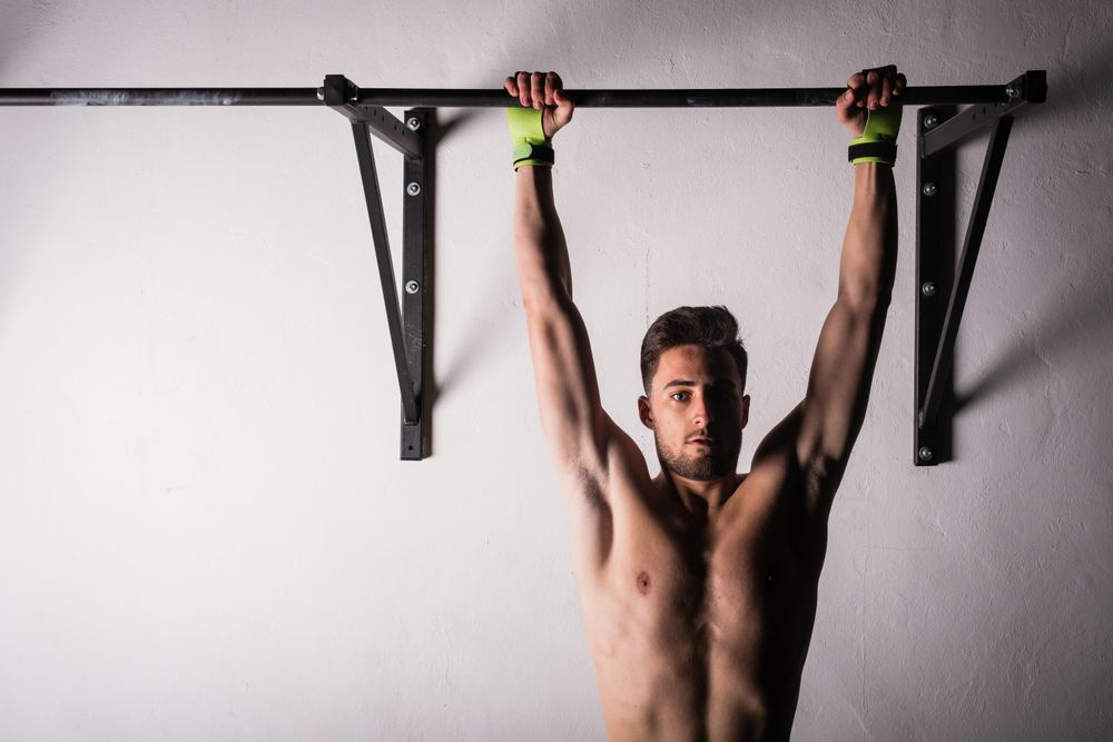 Man hanging on bar near wall in gym