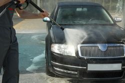 A man washes a car in a manual car wash. Clear car