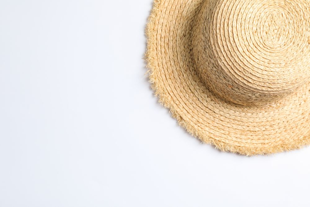 Pretty straw hat on neutral background. Space for text, top view