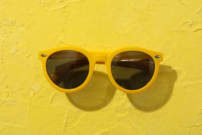 Sunglasses on yellow background, close up. Summer vacation