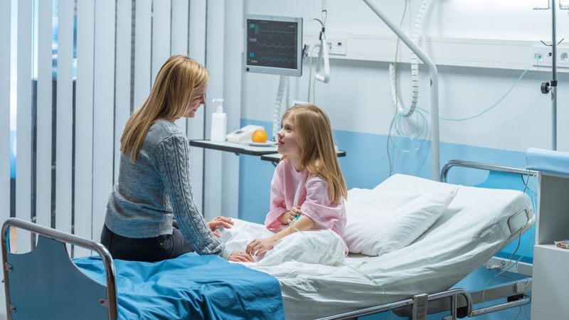 Healed Little Girl Sits on a Hospital Bed and Chats with Her Mother