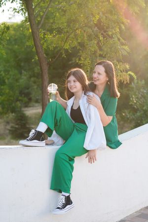 Mom and teenage daughter drink soft drinks on walk