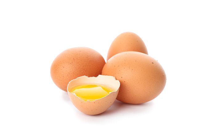 Chicken eggs and half broken egg with yolk  isolated on blank background